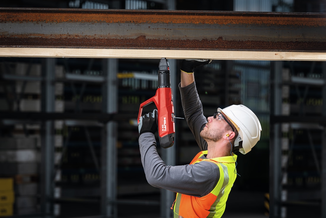 Worker fastening wood to a metal beam with the DX 6