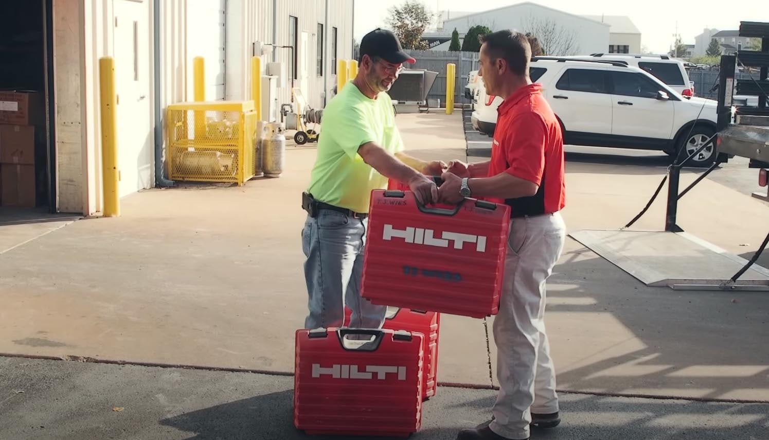 two men wearing hard hats on a construction site looking at a te 6-a cordless rotary hammer drill