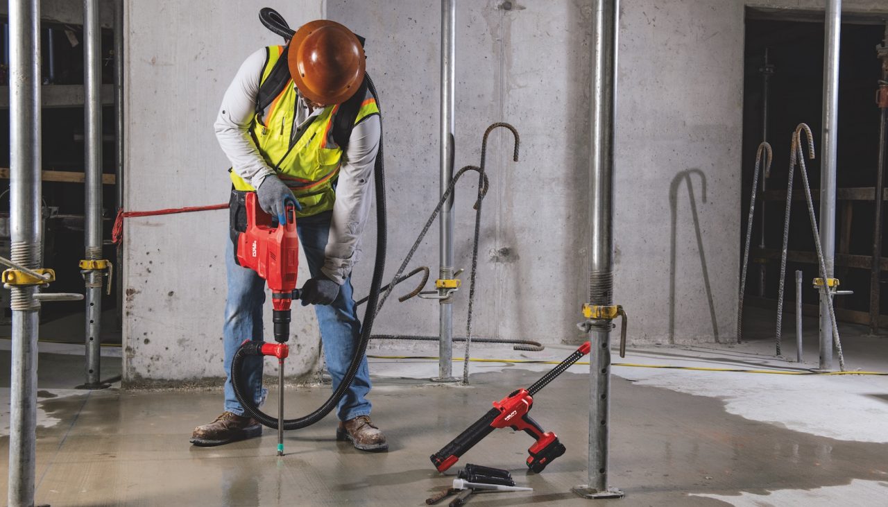 Construction worker using Hilti SafeSet installation method with VC 140-2-22 "vac-pack" vacuum and TE 60-22 cordless rotary hammer. HDE 500-22 cordless adhesive dispenser, HIT-RE 100 adhesive anchor