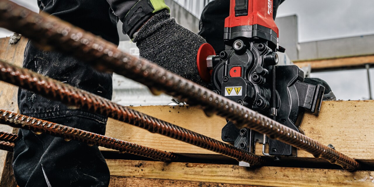 The NRC 6-22 Rebar cutter lined up against wood, about to cut rebar.